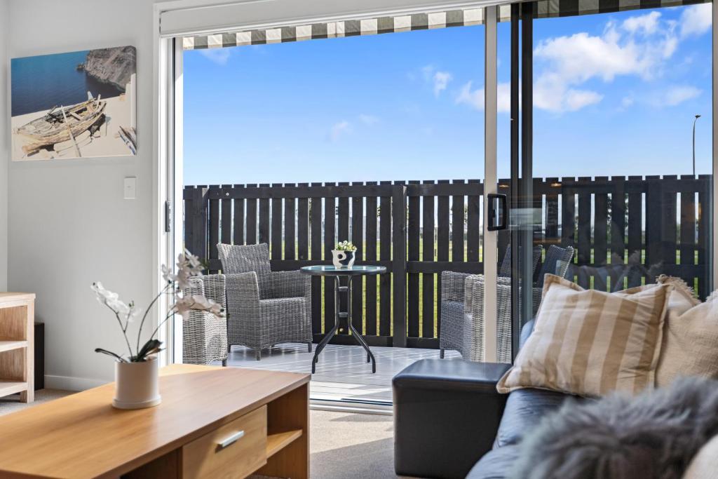 a living room with a couch and a large window at Papamoa Beach Retreat in Tauranga