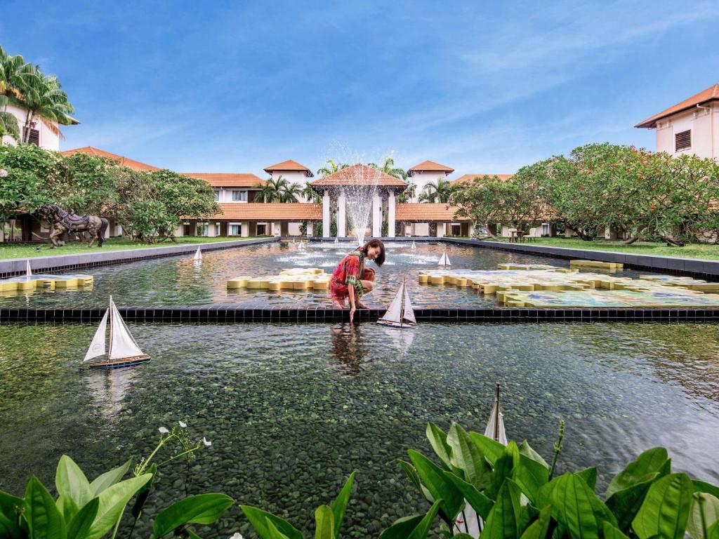 a woman playing with toy boats in the water at Sofitel Singapore Sentosa Resort & Spa in Singapore