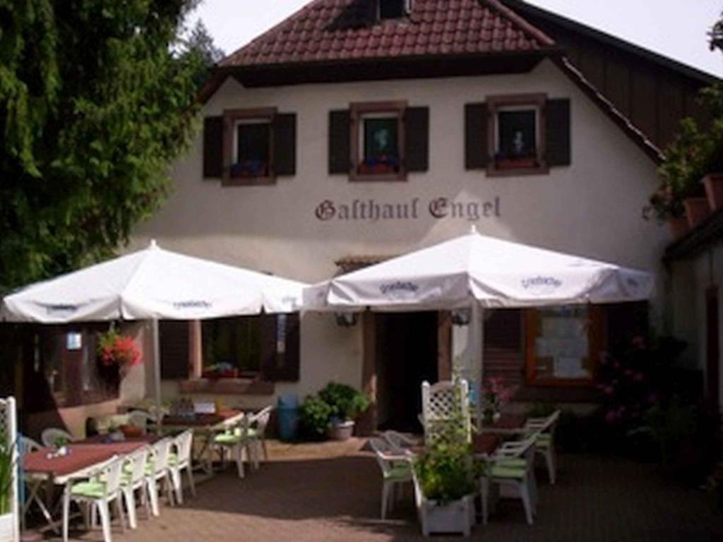 un restaurante con mesas y sombrillas frente a un edificio en Landgasthaus zum Engel, en Freiamt