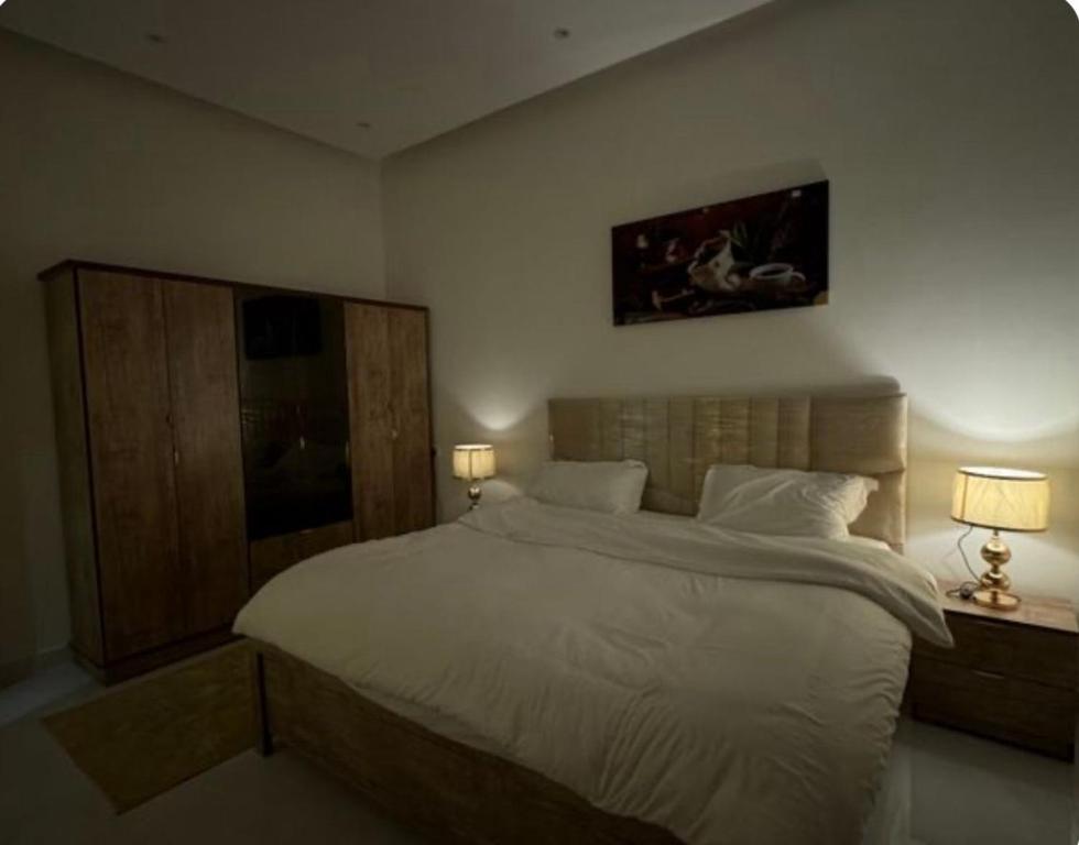 ハフル・アル・バティンにあるشقه وغرفه وصاله ومطبخ كامل هاديه عائليهの大きな白いベッドと2つのランプのある寝室