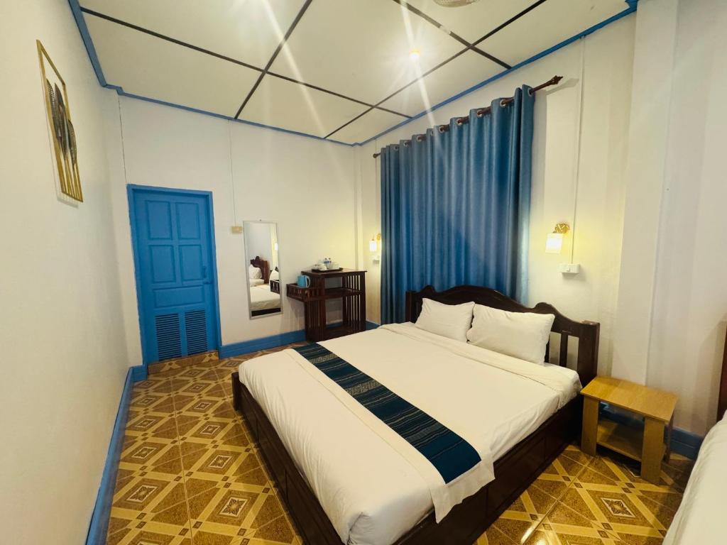 a bedroom with a bed and a blue door at Le Jardin 2 Organique Guesthouse Vang Vieng in Vang Vieng