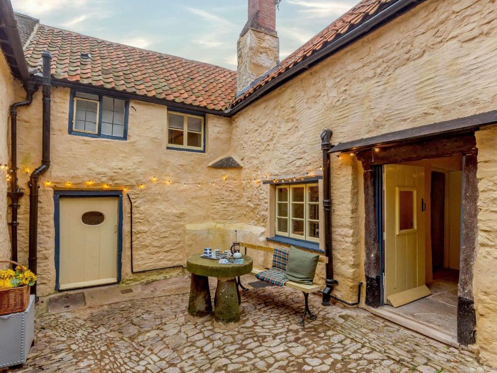 an outside courtyard of a building with a table and a bench at 4 Bed in Dunster 90504 in Dunster