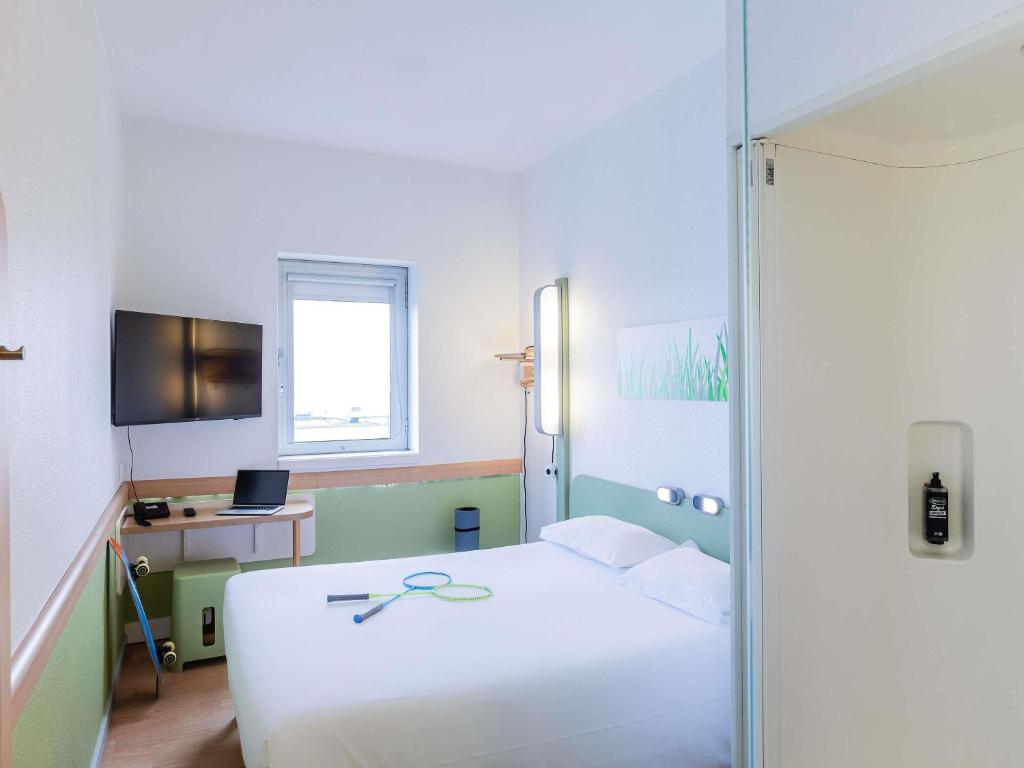 a bedroom with a white bed and a desk and a window at Hotel ibis Budget Porto Gaia in Vila Nova de Gaia
