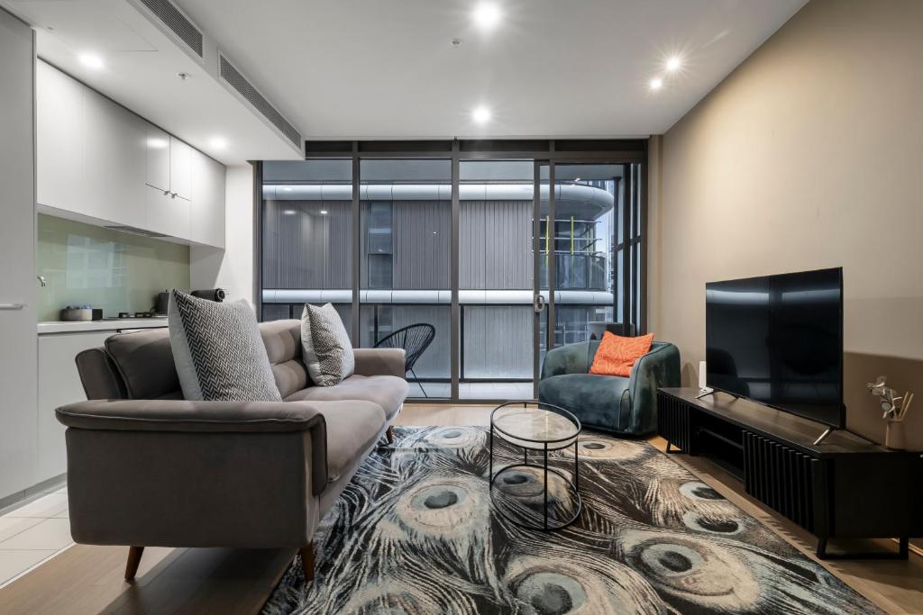 a living room with a couch and a tv at Elegant City Fringe Condo w Pool & FREE Parking in Melbourne