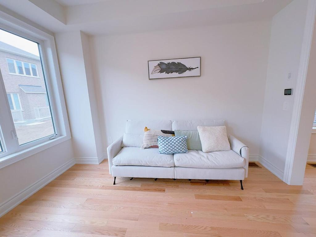 a living room with a white couch and a window at Vantage stay Modern 4BR townhouse pickering in Pickering