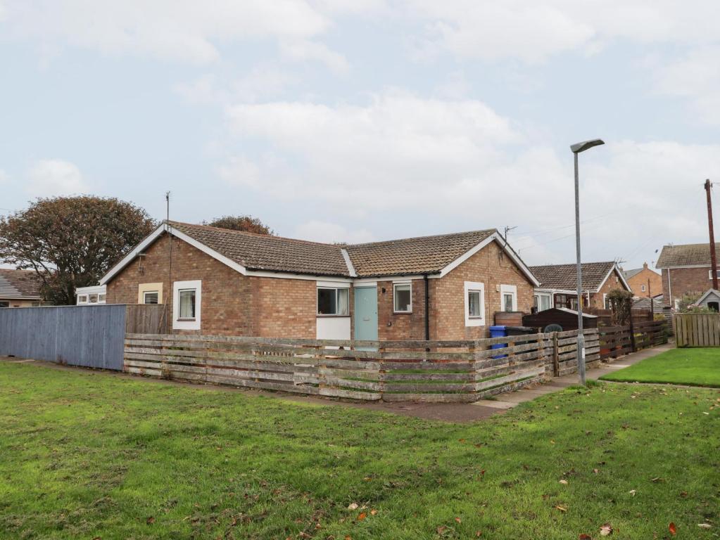 a brick house with a wooden fence in a yard at 51 Longstone Park in Chathill