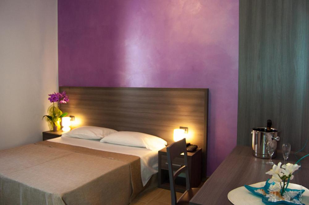 1 dormitorio con cama y pared púrpura en Le Tre Stelle Marine, en Acquedolci