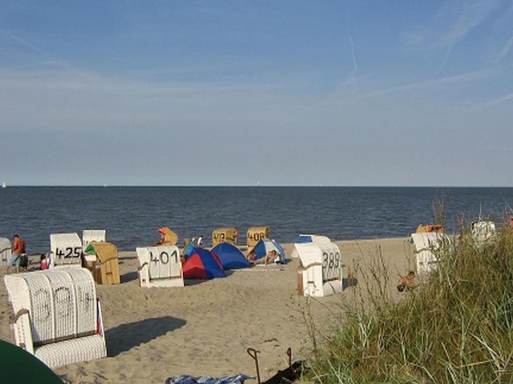 einen Strand mit Liegestühlen und Sonnenschirmen und dem Meer in der Unterkunft Ferienwohnungen Tenge in Hooksiel