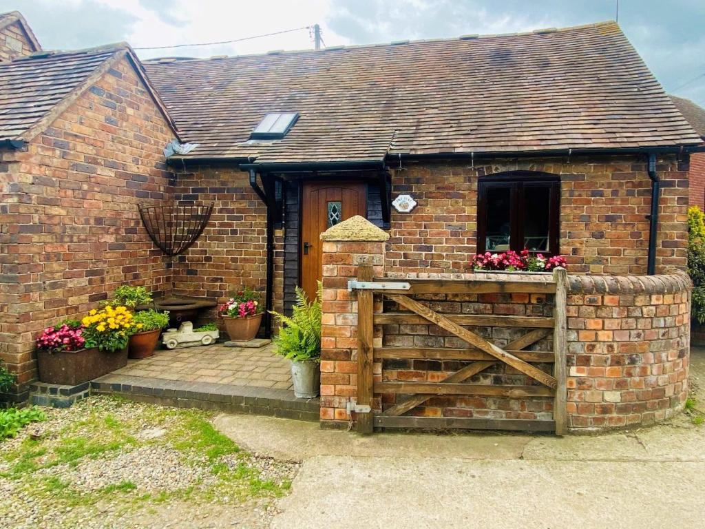 a brick house with a wooden gate and flowers at 1 Bed in Ironbridge 80726 in Leighton
