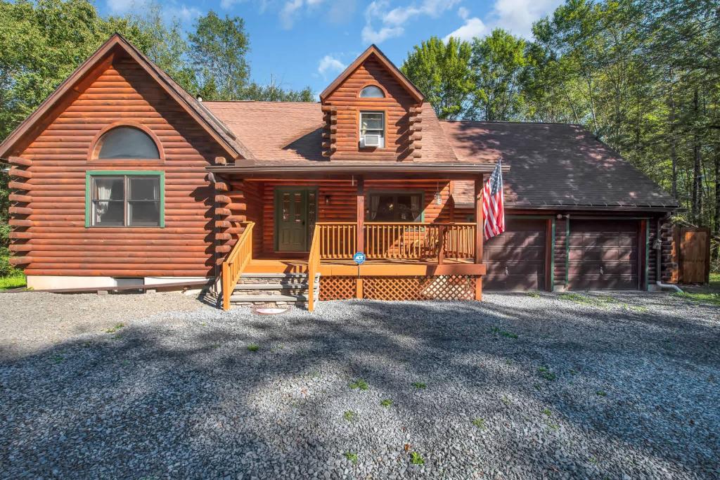 a log home with a flag in front of it at Secluded Log Cabin with Hot Tub Fire Pit Game Room in Newfoundland