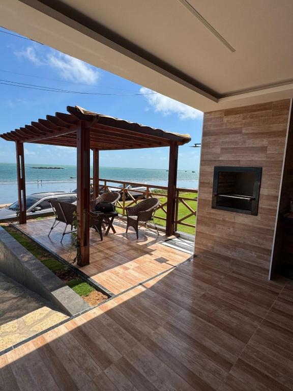 a patio with a fireplace and a view of the ocean at Casa da Maré Pé na areia Suítes climatizadas e deck vista mar in Icapuí