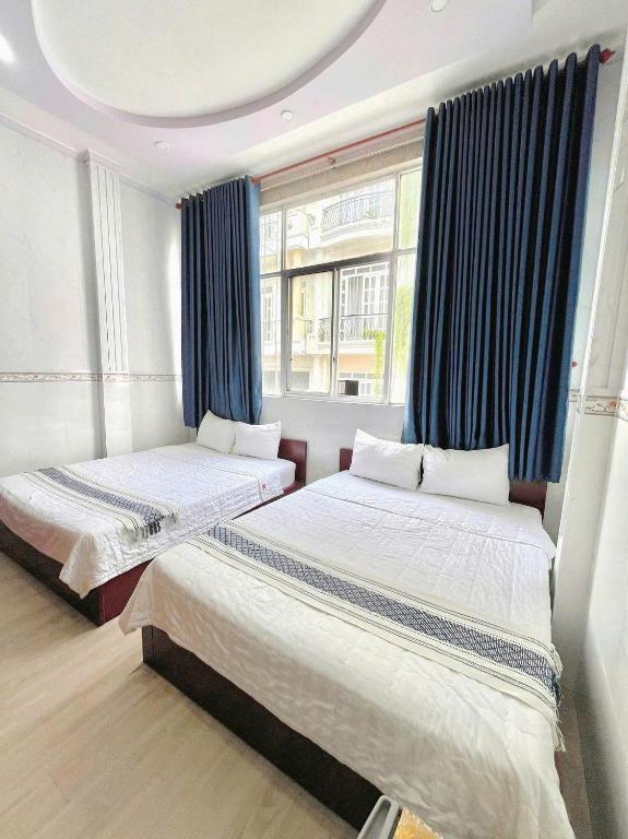 two beds in a room with blue curtains at My Kim Hotel - Ngay Bến Ninh Kiều in Can Tho