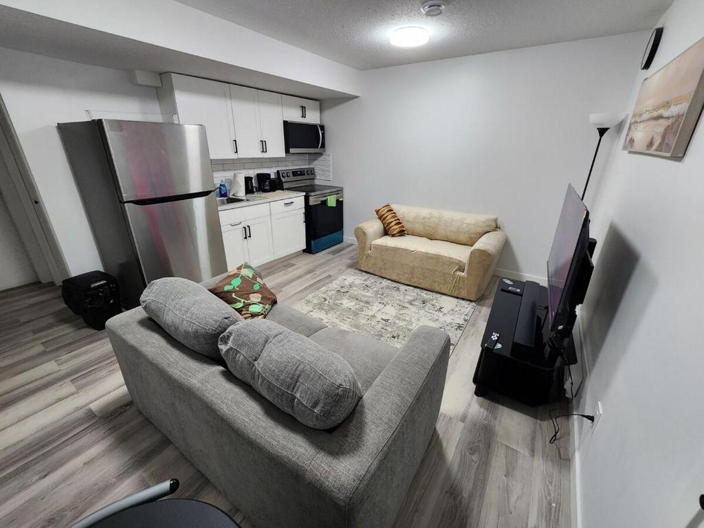 a living room with a couch and a kitchen at Cozy Oasis in the Greens in Regina
