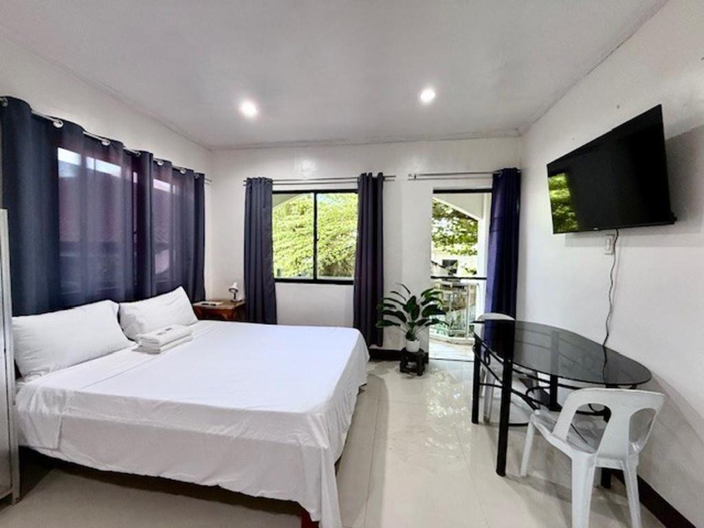 a bedroom with a white bed and a glass table at DRB Siargao Apartments in General Luna
