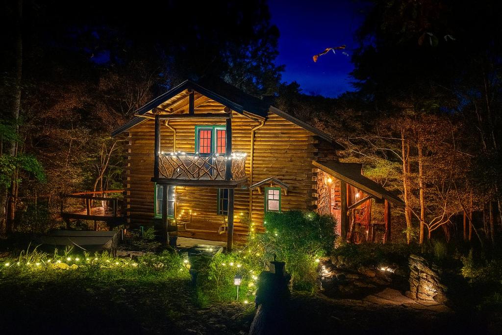 ein Holzhaus mit Lichtern im Hof bei Nacht in der Unterkunft Crabapple-Secluded cabin with pond creek access, hot tub, fire pit in Blue Ridge in Morganton