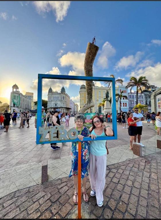 two girls are holding up a sign in a square at Mangue Oranje Hostel - no bairro do Recife Antigo - Old Town in Recife