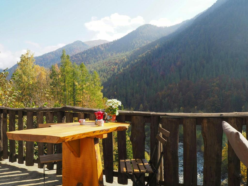 a wooden table on a deck with a view of a mountain at Baita In Pietra Con Vista Sulla Valle Di Ala in Ala di Stura