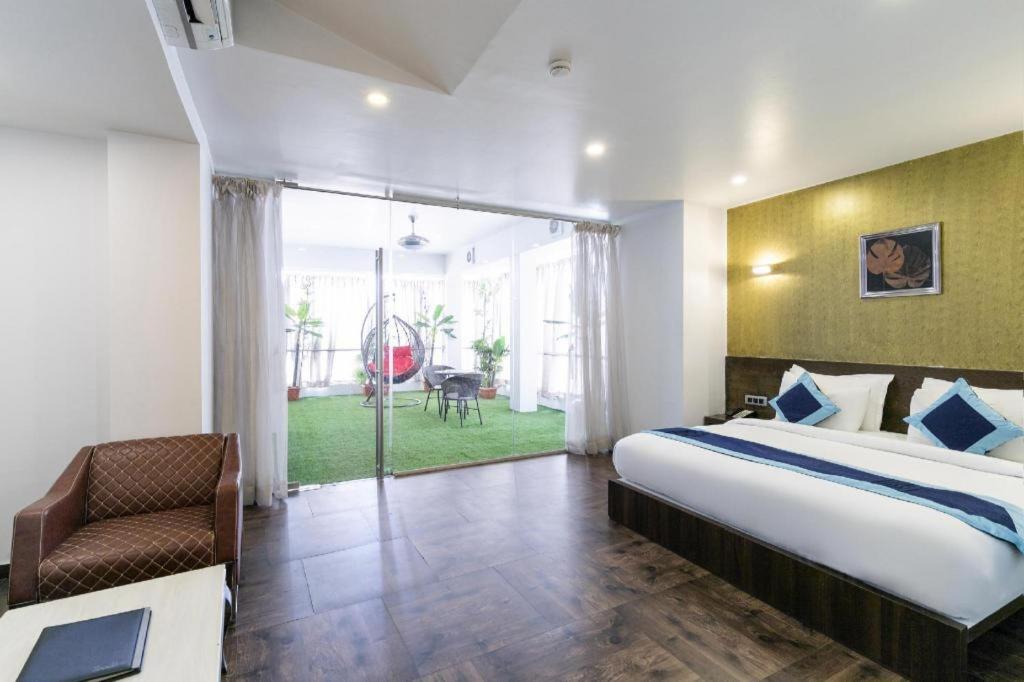 a bedroom with a bed and a chair in a room at Palette - Silver Leaf in Vapi