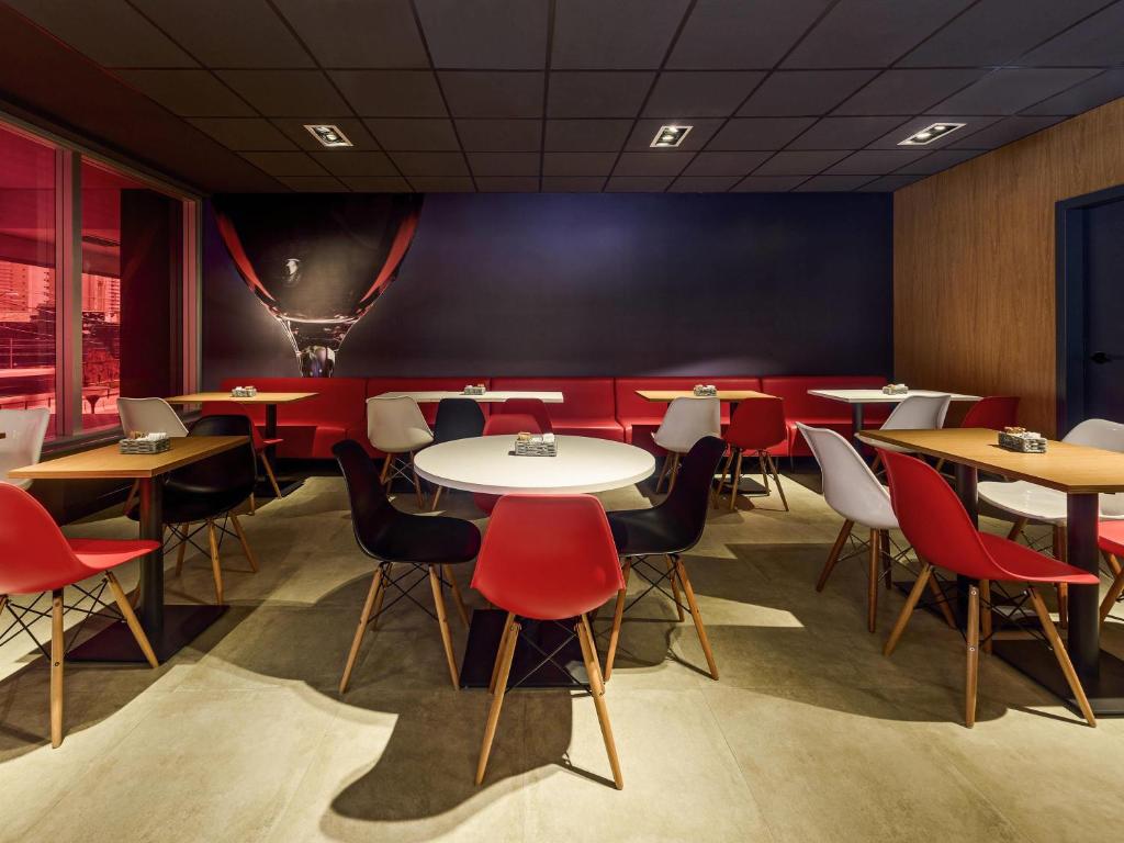 a dining room with tables and red chairs at ibis Sao Paulo Ibirapuera in Sao Paulo