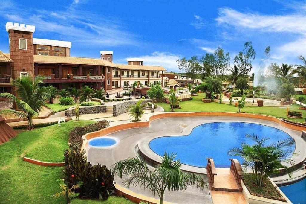 a resort with a large swimming pool in the yard at Hudson Resorts in Pondūr