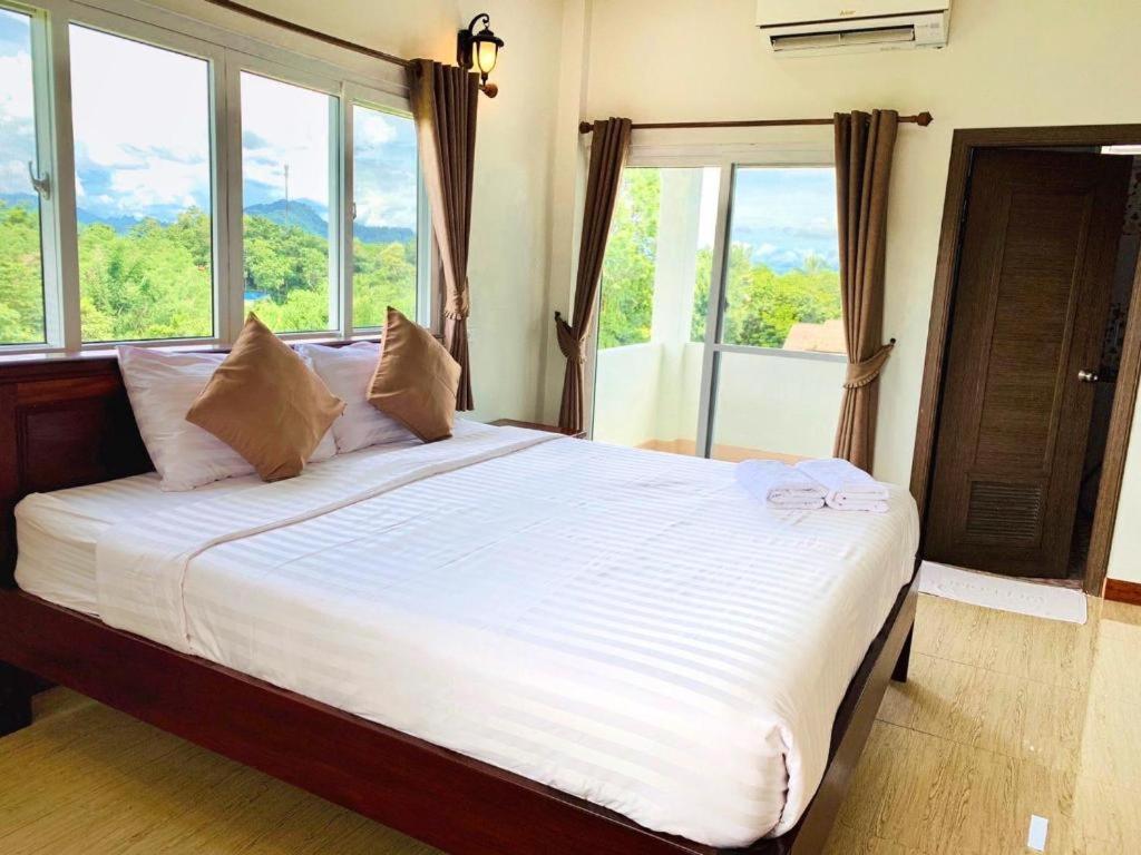 a bedroom with a large bed with large windows at janwareeresort in Sangkhla Buri