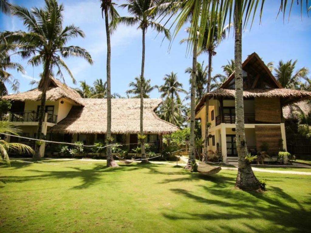 a house with palm trees in front of it at Buddha Resort in Catagnan