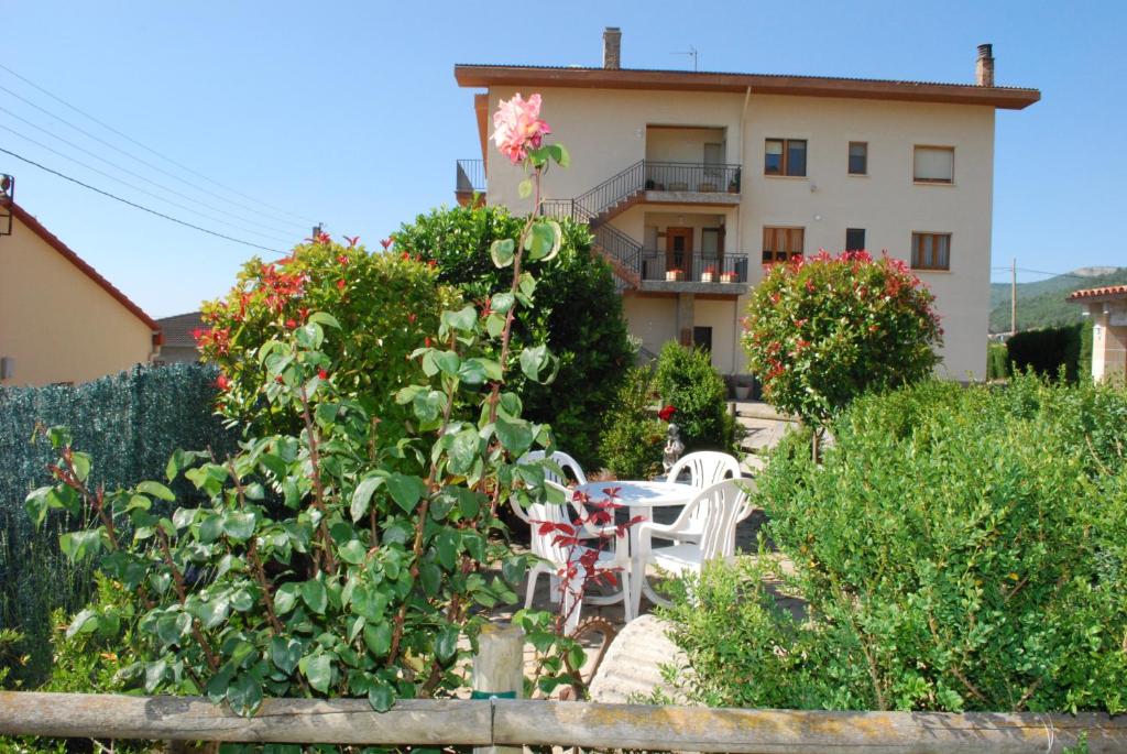 einen Garten mit einem Tisch und Stühlen vor einem Gebäude in der Unterkunft Cal Serveró in Peramola