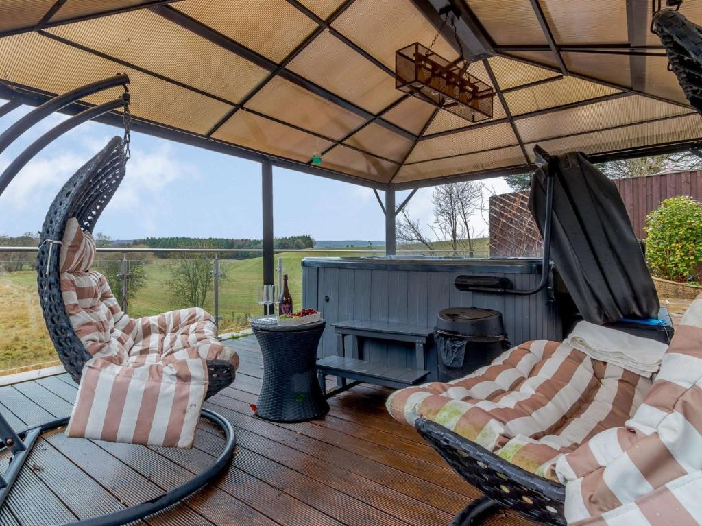 a porch with two chairs and an umbrella at 4 Bed in Gleneagles 86381 in Auchterarder