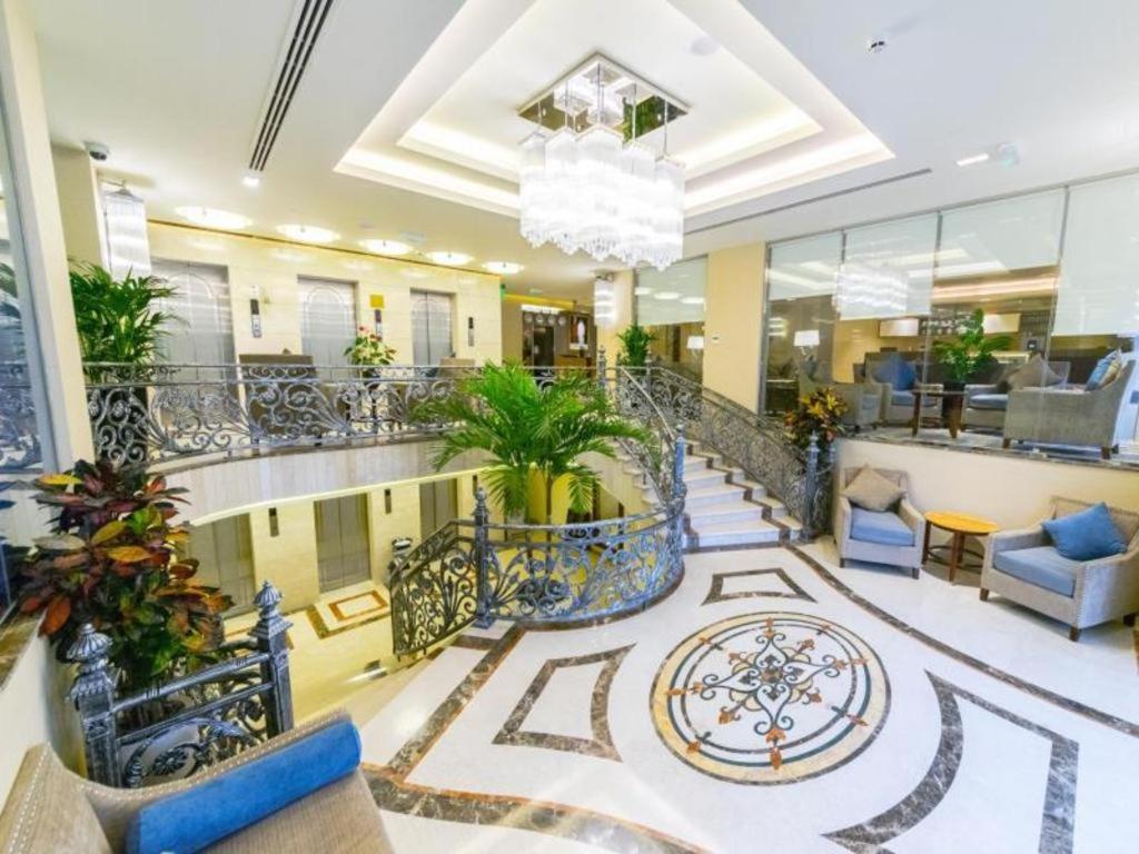 a lobby with a staircase with blue chairs at Gulf Pearls Hotel in Doha