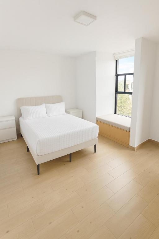 a white bedroom with a bed and a window at Depamor in Morelia
