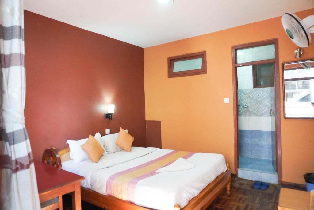 Un dormitorio con una cama con paredes naranjas y una ventana. en Khangsar Home, en Katmandú