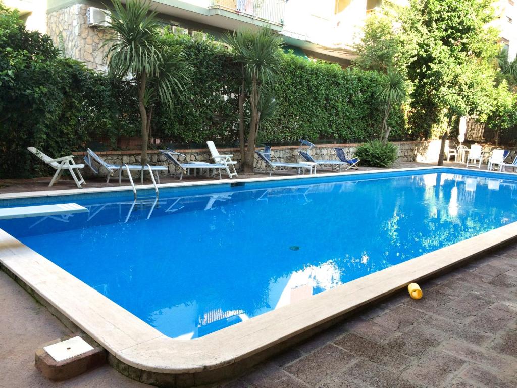 una grande piscina blu con sedie a sdraio accanto a un edificio di The Pool House Suite a Sorrento