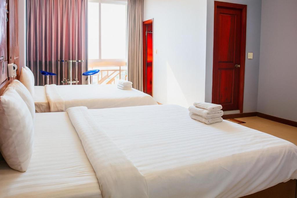 deux lits dans une chambre d'hôtel avec des serviettes dessus dans l'établissement Bình Minh Hotel HCM, à Hô-Chi-Minh-Ville