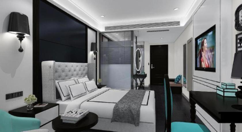 a bedroom with a large white bed and a desk at Xana Hotelle Shijiazhuang Zhongchu Plaza Shizhuang Metro Station in Shijiazhuang