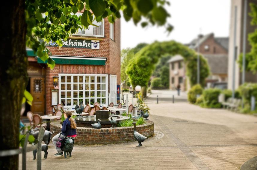 Eine Frau, die zwei Hunde vor einem Gebäude führt. in der Unterkunft Hotel Restaurant Knechtstedener Hof in Dormagen