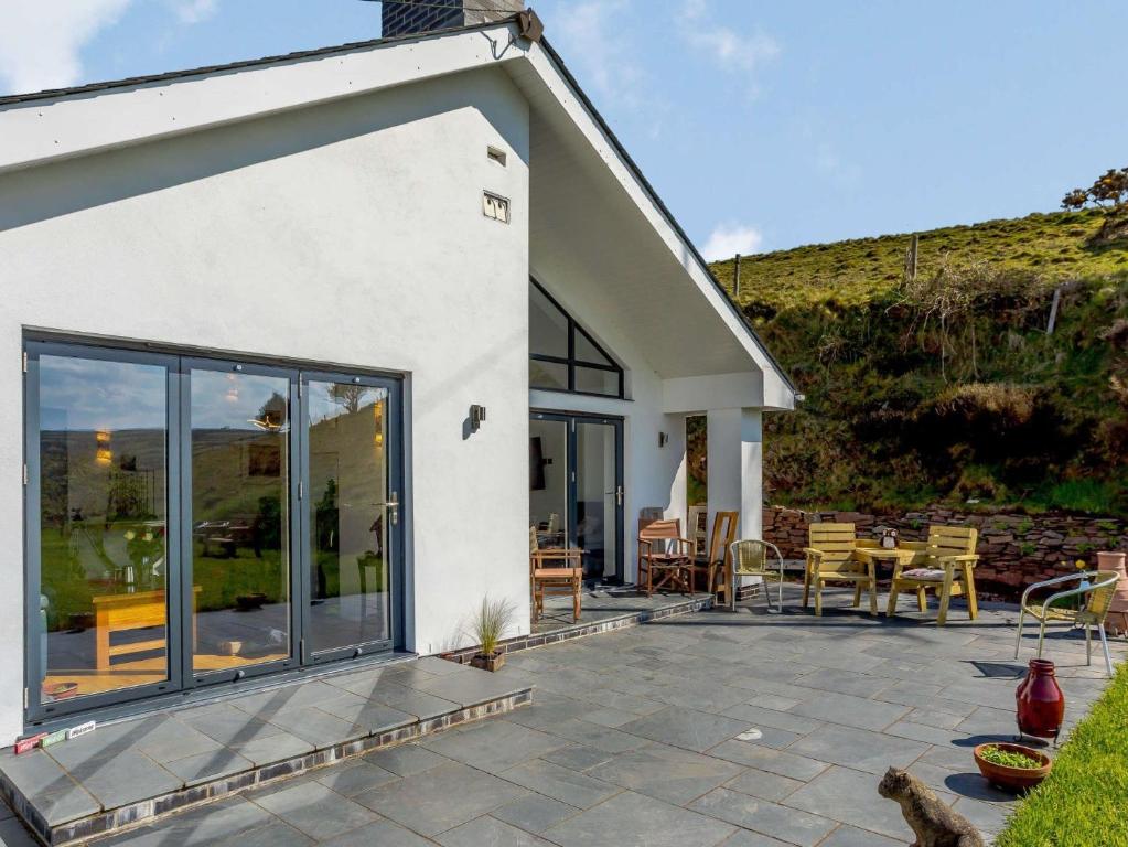 a patio with chairs and tables in front of a house at 4 Bed in Combe Martin 82500 in Trentishoe