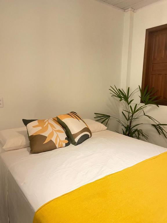 a bed with two pillows on top of it at Sol Suítes Caraíva in Porto Seguro