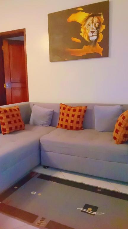 een woonkamer met een blauwe bank en oranje kussens bij Home sweet Home in Entebbe