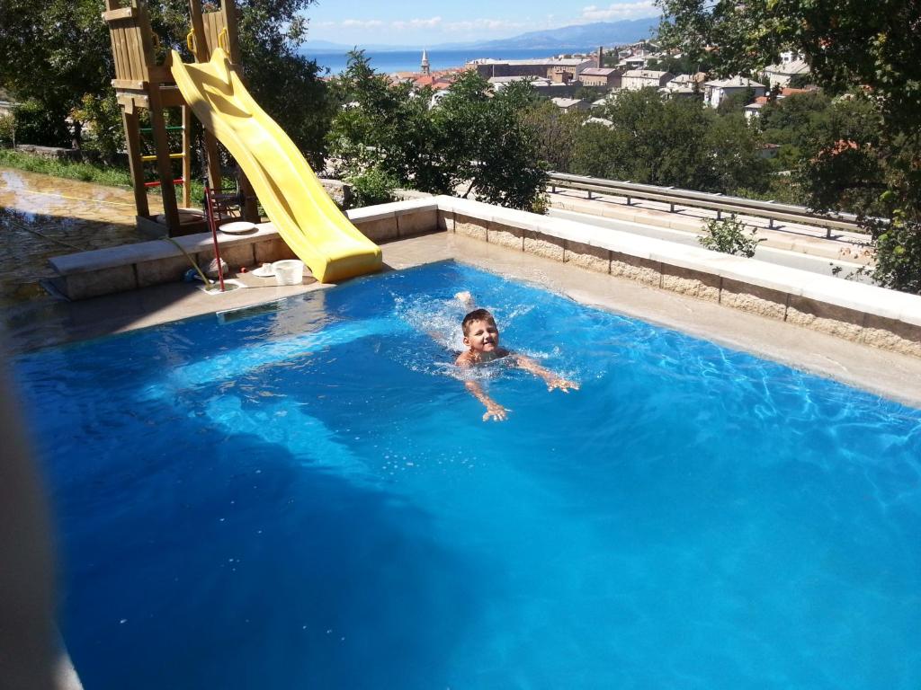 a child swimming in a swimming pool with a slide at BC Apartments in Senj