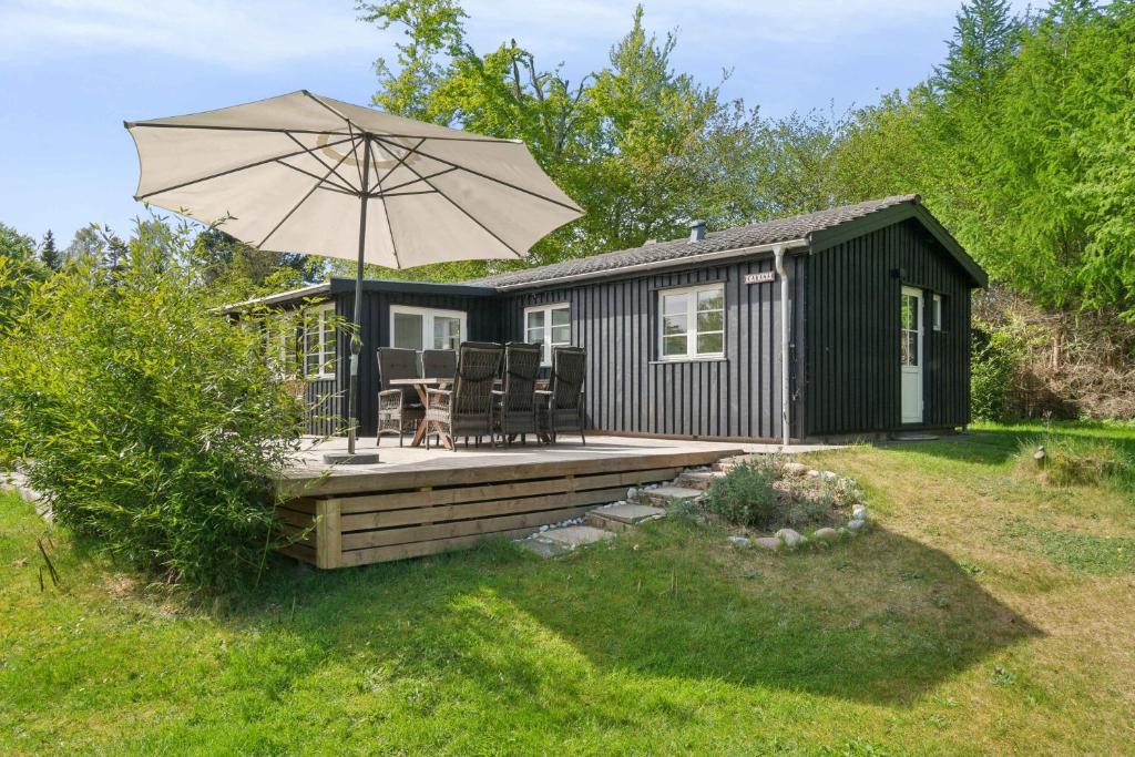 a small cabin with a deck with an umbrella at Cosy Summerhouse With Private Garden in Nyrup