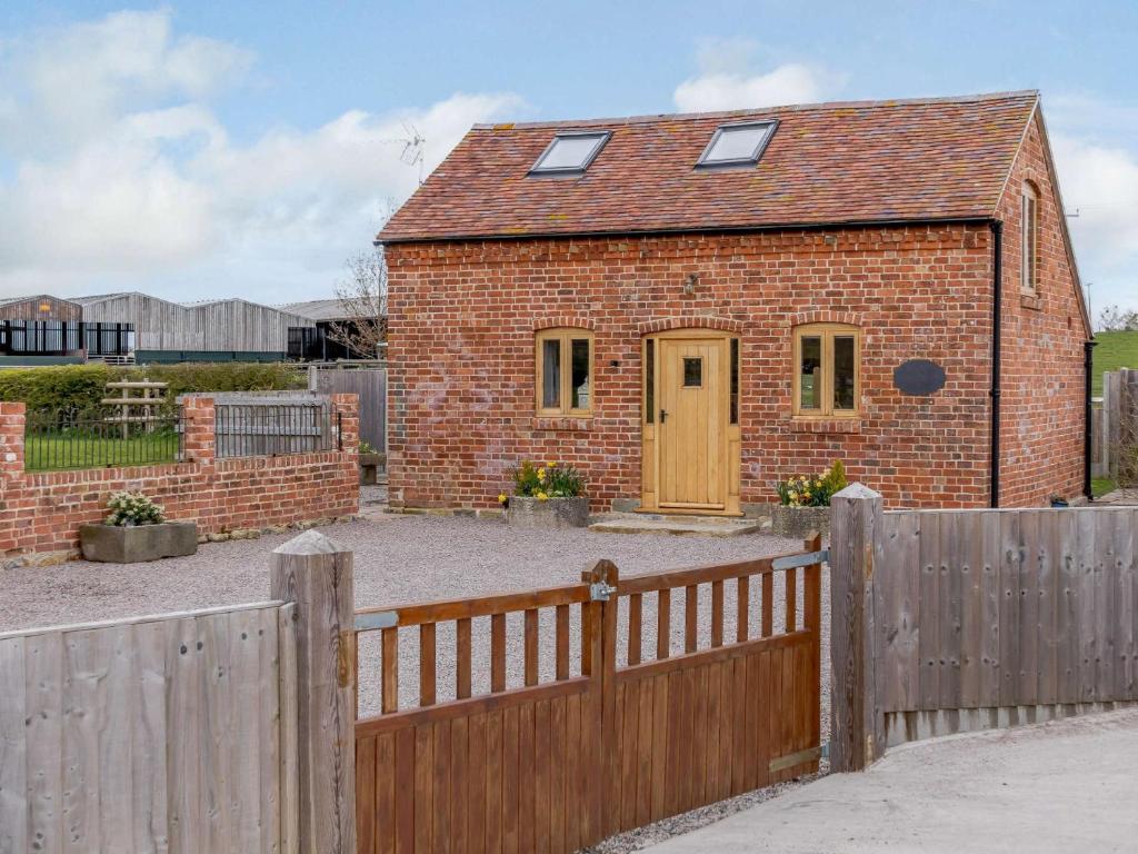 ein Backsteinhaus mit einem Holzzaun davor in der Unterkunft 1 Bed in Cheltenham 60276 in Tirley