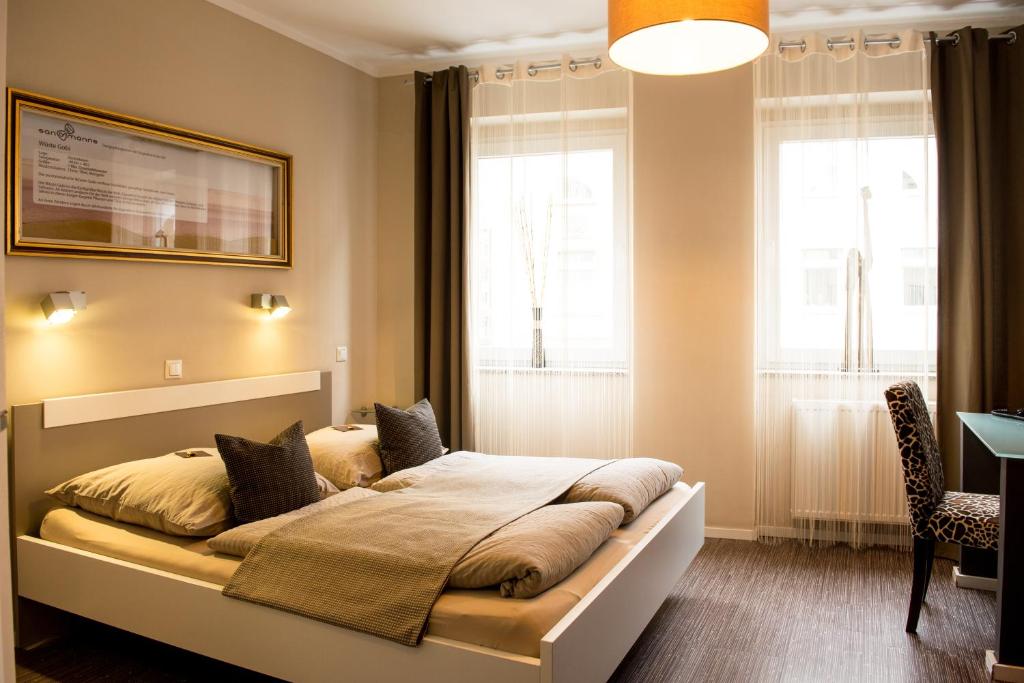 a bedroom with a bed, chair, lamp and window at Hotel Sandmanns am Dom in Cologne