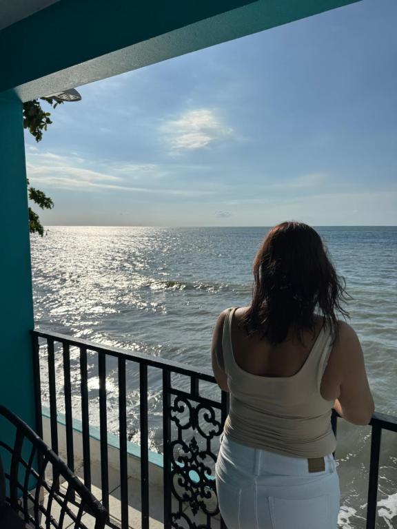a woman standing on a balcony looking at the ocean at Beachfront balcony 2nd floor retreat Sleeps 6 