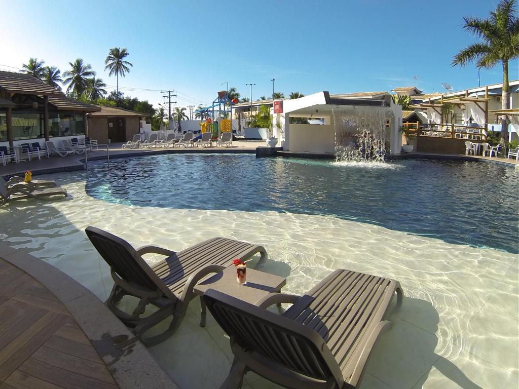 a swimming pool with two chairs and a fountain at Sueds Plaza in Porto Seguro