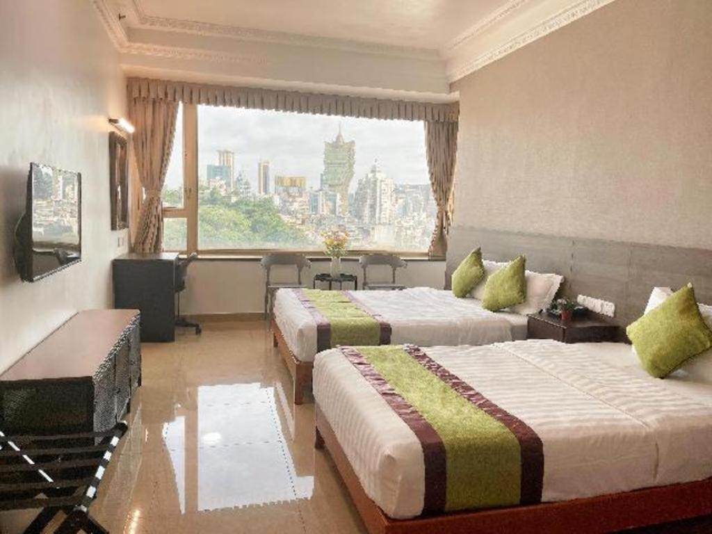a hotel room with two beds and a large window at Grand Harbour Hotel in Macau