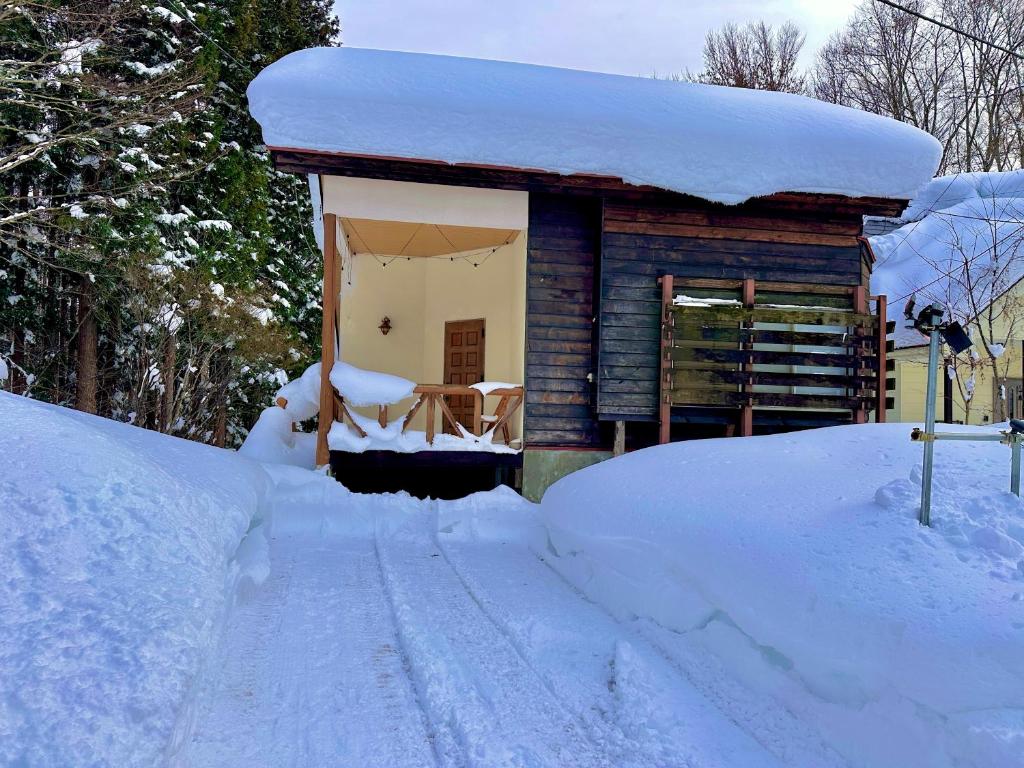 a house covered in snow with a pile of snow at 東京2時間スキー場徒歩3分温泉付 友達や家族と一棟貸 in Sudagai