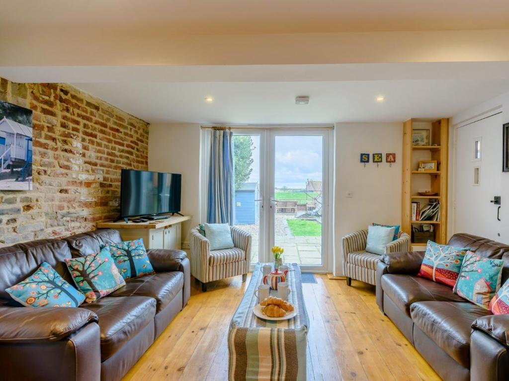 ウェルス・ネクスト・ザ・シーにある3 Bed in Wells-next-the-Sea KT050のレンガの壁のリビングルーム(革製家具付)