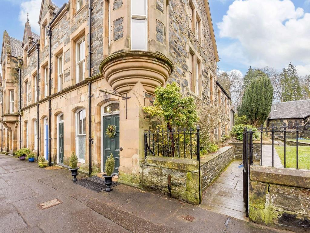 ein altes Steingebäude mit Balkon auf einer Straße in der Unterkunft 5 Bed in Dunkeld 90844 in Birnam
