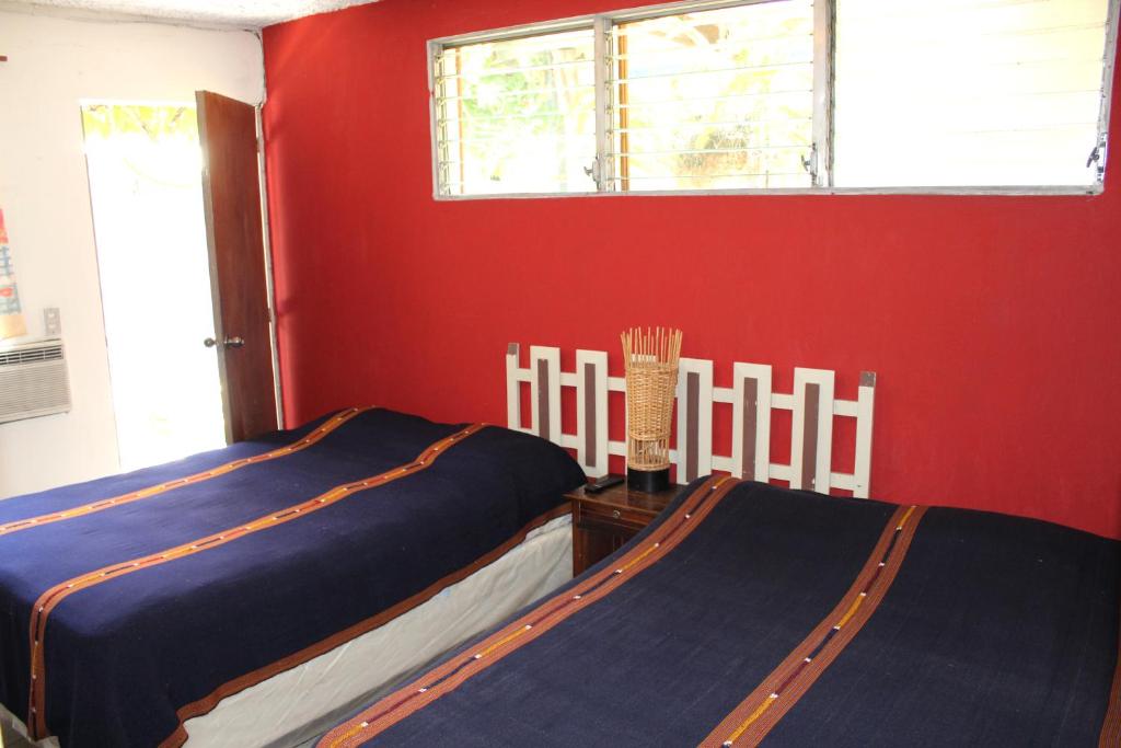 two beds in a room with a red wall at Ximenas Guest House in San Salvador
