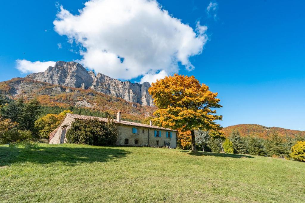 an old house on a hill with a tree and a mountain at Gîte Les Ailliers in La Chaudière